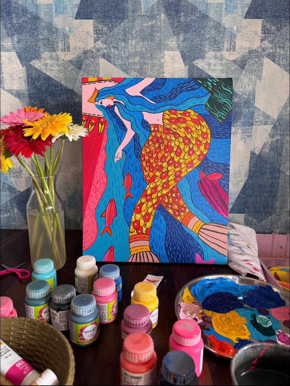A bright painting beside flowers and paint pots