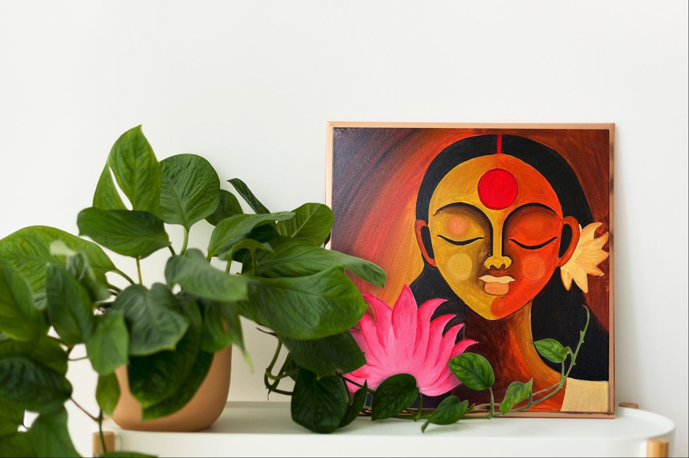 A framed portrait resting on a shelf with plants