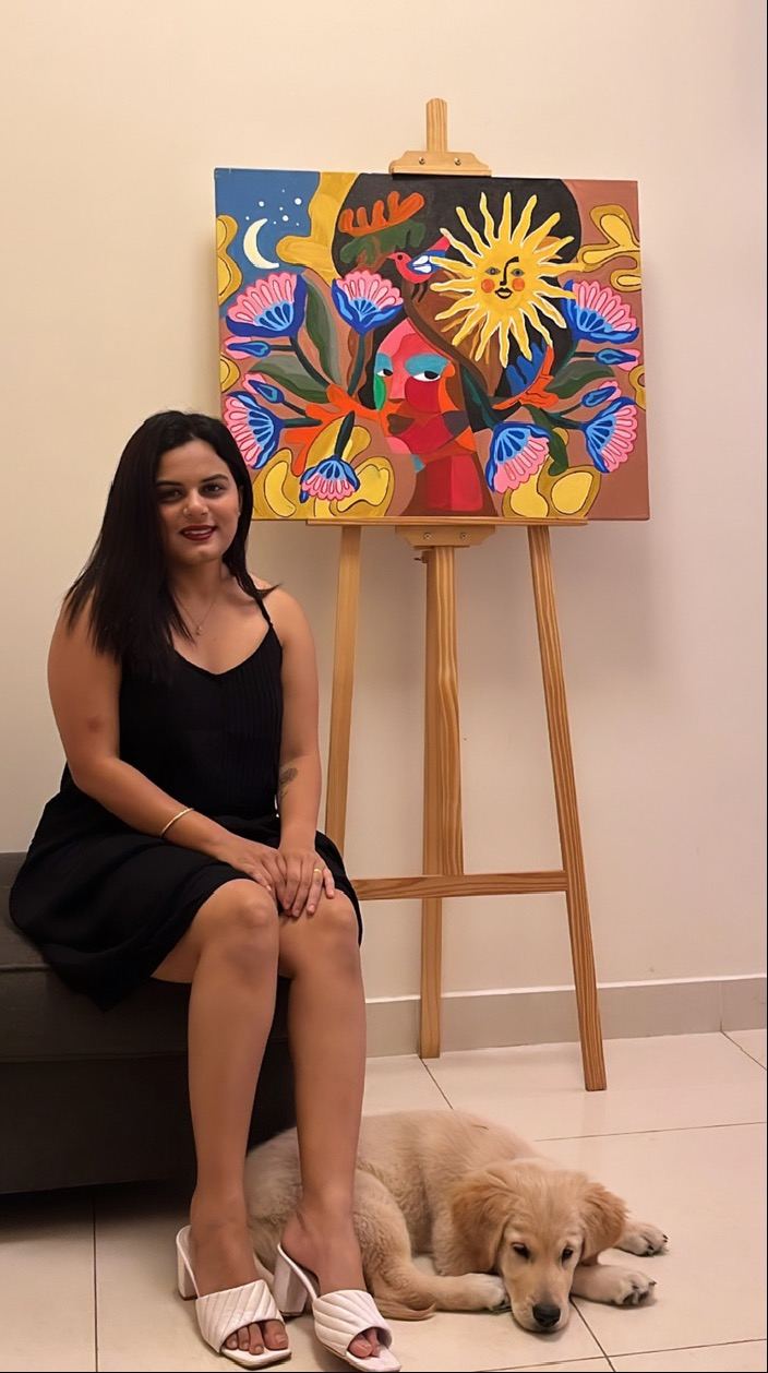Rucha seated with a finished painting and her dog